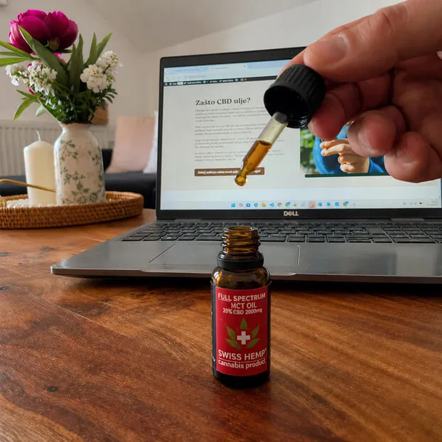 CBD ulje Vitela full spectrum s pipetom iznad bočice, korištenje proizvoda tijekom rada na laptopu