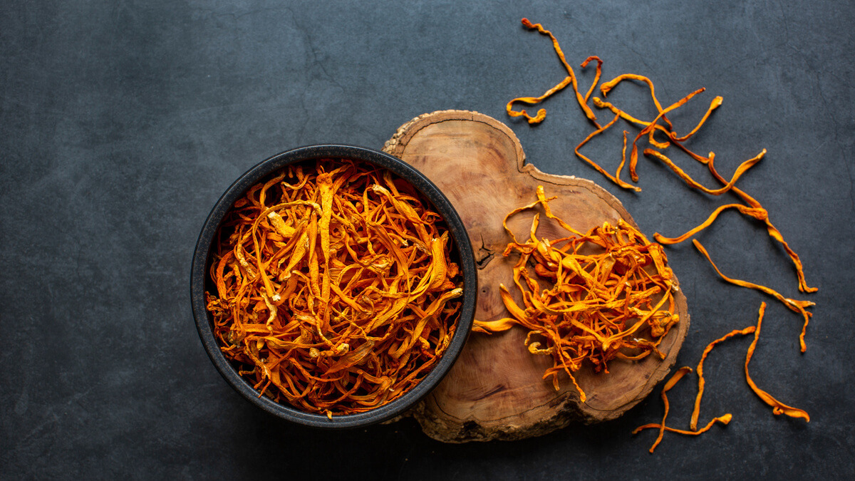 Sušeni Cordyceps gljive u zdjelici na drvenoj podlozi, prirodni superfood za energiju i imunitet